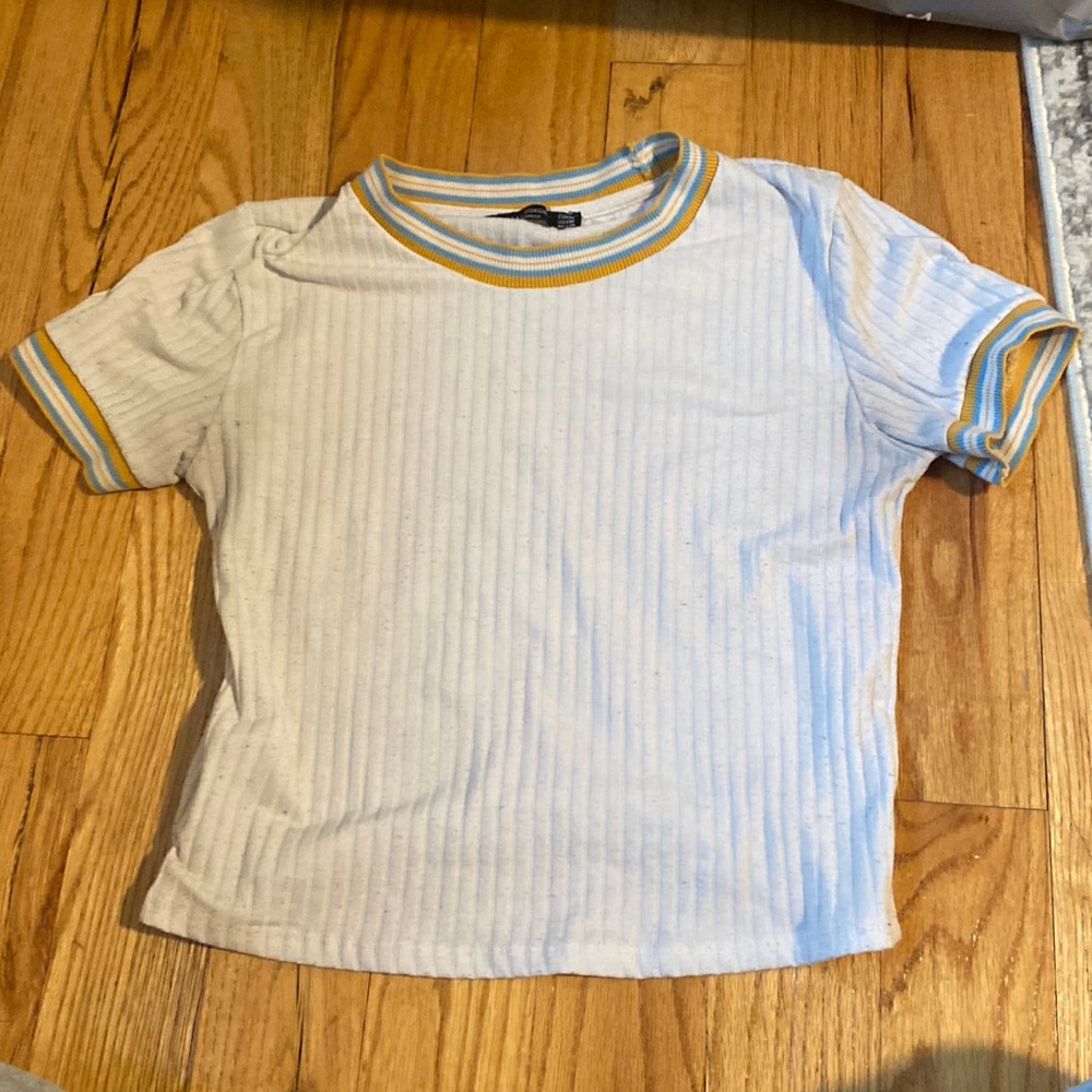White crop top with blue white and yellow around the sleeves and neck